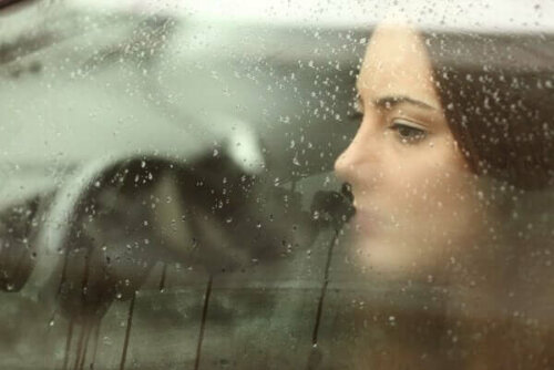 Kvinna som tittar ut genom bilfönstret med emotionellt resonerande för att tänka på någon långt borta