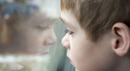 Ledsen pojke, vid fönster, som lider av övergrepp, en av orsakerna bakom narcissistisk personlighetsstörning