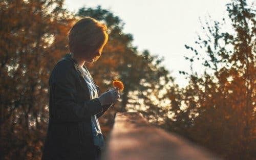 En kvinna med en blomma i färd med att känna sig ensam