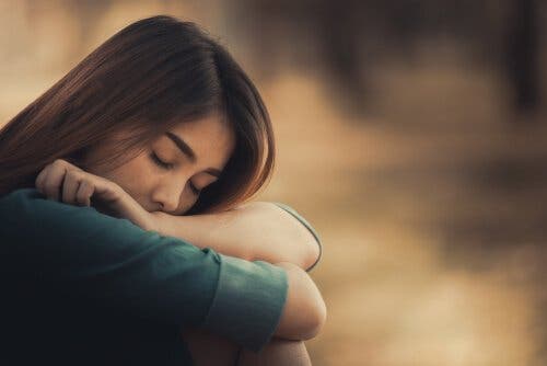 En sorgsen kvinna som vilar på armarna