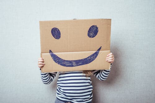 Ett barn bakom en kartong med smiley