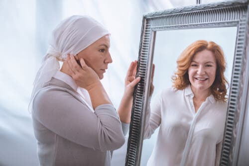 En kvinna med cancer ser sig själv, så som hon såg ut med hår, i spegeln