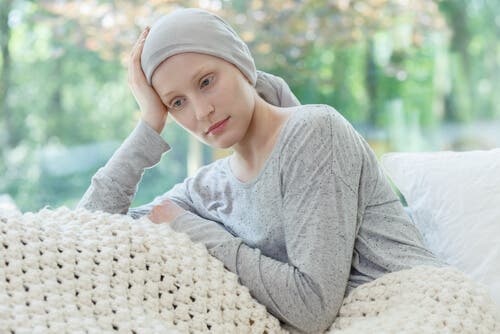 En kvinna med gynekologisk cancer som sitter på en soffa med en huvudduk