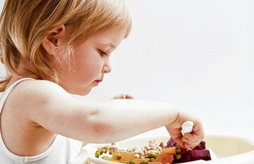 En flicka som äter grönsaker, helt på egen hand