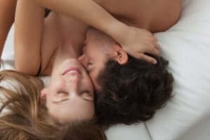 En kvinna och man omfamnar varandra i en säng