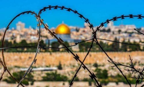 En bild av Jerusalem genom ett taggtrådsstängsel som exempel på heliga värderingar