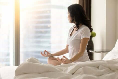 En kvinna som mediterar i sängen