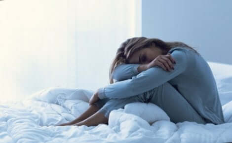 En utmattad kvinna sitter och sover i sängen
