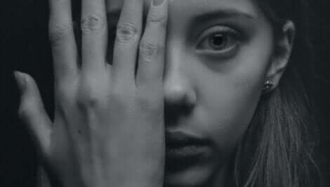 En kvinna som täcker sitt ansikte med handen