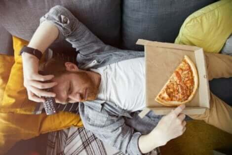 En uttråkad man som äter pizza på soffan