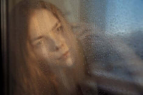 En kvinna som tittar ut genom ett regnigt fönster
