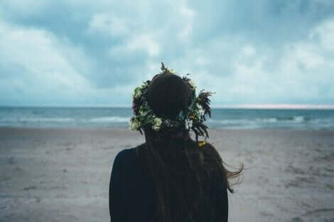En ensam kvinna med blomkrans i håret på en strand