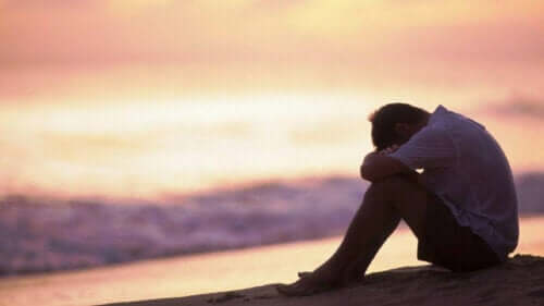 En ledsen man som sitter vid stranden och tänker på yttre känsloreglering
