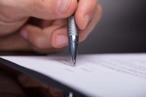En närbild på en hand, en penna och ett formulär