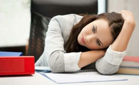 En trött kvinna vilar huvudet på ett skrivbord