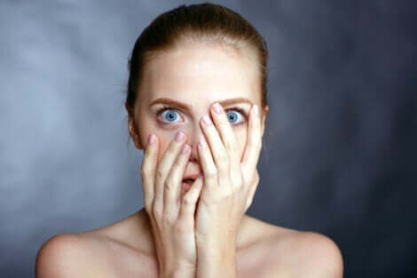 En kvinna med blåa ögon som täcker sitt ansikte