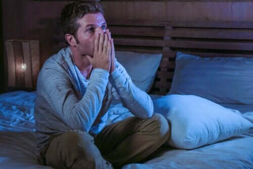 En orolig man sitter upp i sängen