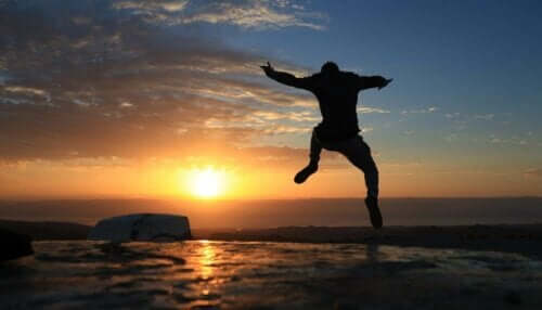 En kille hoppar av glädje framför solnedgången
