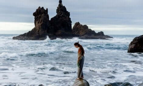 En kvinna som står på en stenbumling vid havet