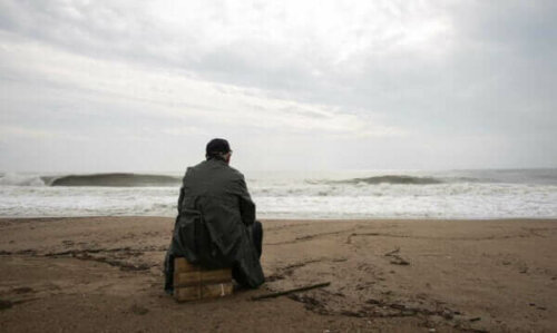 En äldre man sitter på en gråmulen dag vid havet