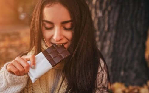 En kvinna njuter av en chokladbit i ett soligt höstväder