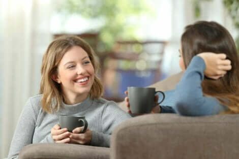 Två kvinnor som dricker kaffe och pratar i en soffa