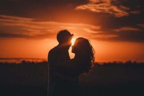 Ett par som står tillsammans framför solnedgången