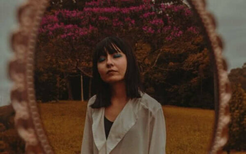 En kvinna som andas djupt, i en park, framför en spegel