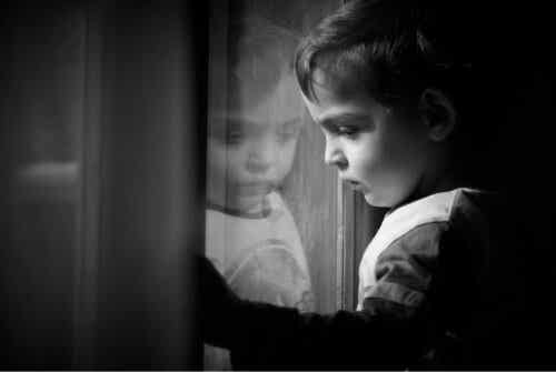 En ledsen pojke som ser ut genom fönstret