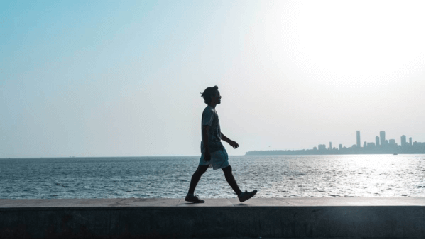 En man som går längs havet